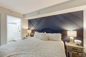 A hotel room with a large bed, a nightstand with a lamp, and a view of the bathroom. - Sandy Daydreams, Unit PH3 (Myrtle Beach)