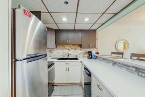 Eine kleine Küche mit einem Edelstahlkühlschrank, einer Spüle und einer Mikrowelle.