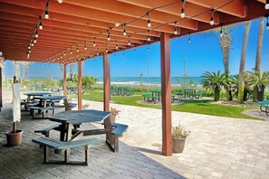 An outdoor patio area with picnic tables and a view of the beach. - Sand Dunes Resort 2443/44 (Myrtle Beach)