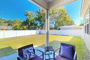 An outdoor patio with two chairs and a small table, surrounded by a white fence and trees. - Sun and Sand Retreat (Myrtle Beach)
