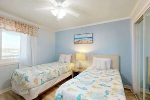 A room with two beds, a ceiling fan, a painting, and a window with curtains. - Ocean Wave Retreat Home (North Myrtle Beach)