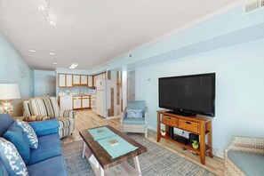 Uma sala de estar com sofá, poltrona e televisão sobre um suporte de madeira.