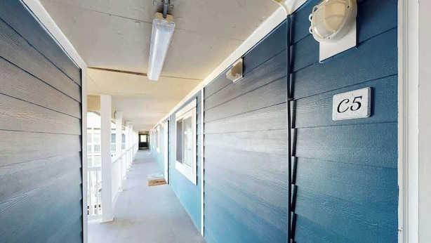 Corredor com parede azul e porta branca identificada com 'C5'.