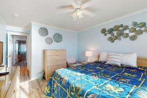 Ein Schlafzimmer mit Bett, Deckenventilator, Kommode und Wanddekoration.