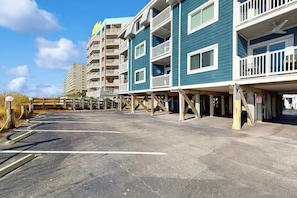 A multi-story hotel with balconies and a parking area. - Ocean Wave Retreat Home (North Myrtle Beach)