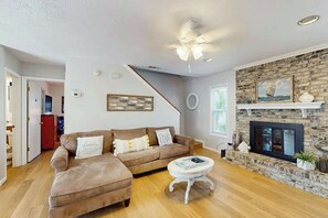 A living room with a sectional sofa, a fireplace, and a staircase. - Tide the Knot At Last (North Myrtle Beach)
