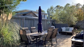 En udendørs terrasse med spisebord, stole, sofa og parasol.