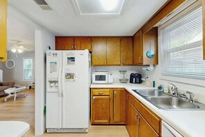 Eine kompakte Küche mit Holzschränken, einem Kühlschrank, einer Mikrowelle und einem Spülbecken.
