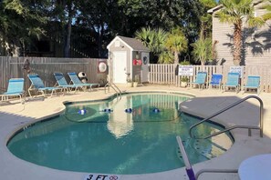 A swimming pool with lounge chairs, a lifeguard station, and a fenced area with palm trees. - Tide the Knot At Last (North Myrtle Beach)