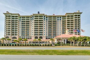 A multi-story hotel with a central courtyard, balconies, and a flag. - Tilghman Condos #1018 (North Myrtle Beach)