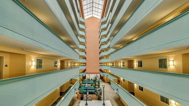 A hotel corridor with multiple floors, a central seating area, and a skylight. - Tilghman Condos #1217 (North Myrtle Beach)