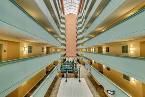 A hotel corridor with multiple floors, a central seating area, and a skylight. - Tilghman Condos #1217 (North Myrtle Beach)