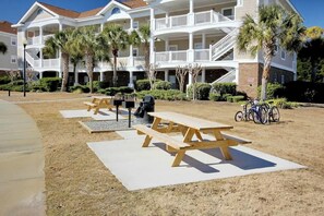 A beachfront property with a two-story building, outdoor seating, and bicycles. - Palmy Days at Ironwood 424 (North Myrtle Beach)