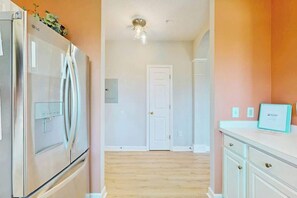 A kitchen with a stainless steel refrigerator, a white door, and a countertop with a framed certificate. - Palmy Days at Ironwood 424 (North Myrtle Beach)