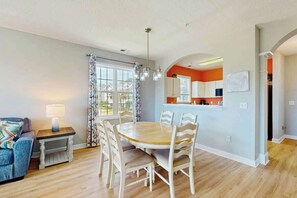 A dining area with a round table and chairs, a sofa, and a lamp. - Palmy Days at Ironwood 424 (North Myrtle Beach)
