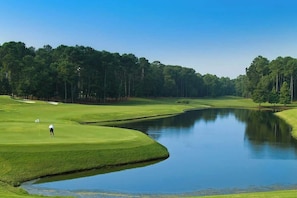 A golf course with a water hazard and a flag on the green. - Starfish Retreat at The Havens 1434 (North Myrtle Beach)