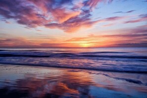 A sunset over a beach with waves reflecting the sky. - Starfish Retreat at The Havens 1434 (North Myrtle Beach)