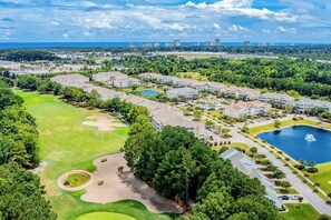 A golf course with a clubhouse, a swimming pool, and residential buildings. - Starfish Retreat at The Havens 1434 (North Myrtle Beach)