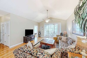 A living room with a sofa, television, and a ceiling fan. - Chillville Unit 1635 (North Myrtle Beach)