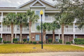 A multi-story residential building with a brick facade, balconies, and palm trees. - Chillville Unit 1635 (North Myrtle Beach)