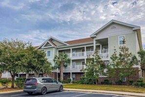 Um edifício residencial de vários andares com um estacionamento em frente.