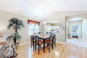 A dining area with a round table and chairs, a potted plant, and a view into the kitchen. - Chillville Unit 1635 (North Myrtle Beach)