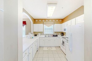 A kitchen with white cabinets, a central island, and a window with blinds. - Chillville Unit 1635 (North Myrtle Beach)