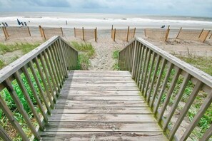 Eine Holztreppe führt zu einem Strand mit einem sandigen Pfad.