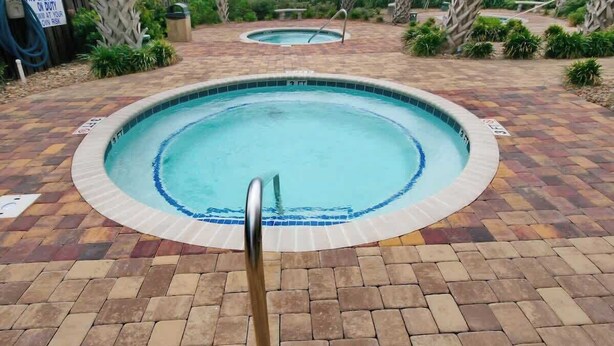 A swimming pool with a tiled edge, surrounded by a brick patio. - Cozy Beach Rendezvous at The Palace Resort (Myrtle Beach)