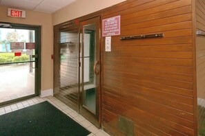 A hotel entrance with an exit sign, a notice about age restrictions, and a glass door. - Cozy Beach Rendezvous at The Palace Resort (Myrtle Beach)