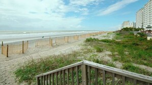 A beach with a wooden walkway leading to a building with multiple floors. - Cozy Beach Rendezvous at The Palace Resort (Myrtle Beach)