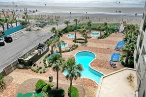Un complexe hôtelier doté de plusieurs piscines, de palmiers et offrant une vue sur la plage.