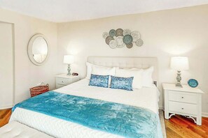 Une chambre à coucher comprenant un lit, deux tables de chevet, un miroir et un élément décoratif mural.