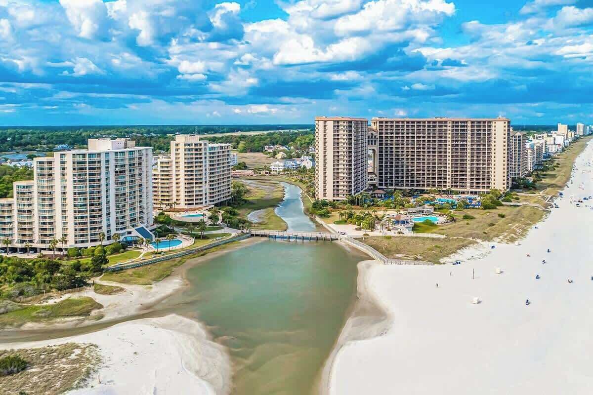 A coastal resort with high-rise buildings, a river, and a beach.