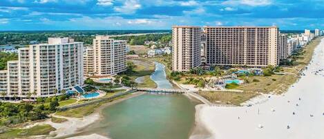 A coastal resort with high-rise buildings, a river, and a beach.
