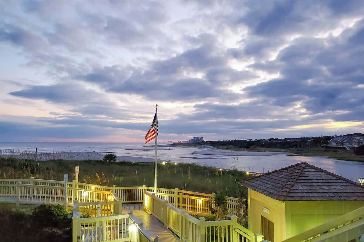 A waterfront property with a flagpole, a small building, and a wooden deck.