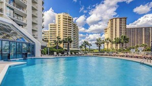 Una piscina con sillas de descanso y palmeras, rodeada de edificios altos.