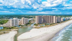 Zona turística costera con varios edificios altos, una playa arenosa y un río.