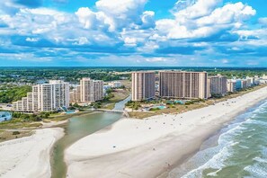 A coastal resort area with multiple high-rise buildings, a sandy beach, and a river.