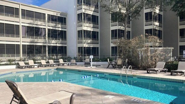 A swimming pool with lounge chairs and a building with multiple floors and windows. - Ocean Creek Unit 2359 (Myrtle Beach)