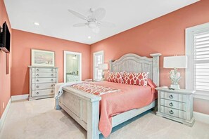 Une chambre à coucher comprenant un lit, une commode, une table de chevet et un ventilateur de plafond.