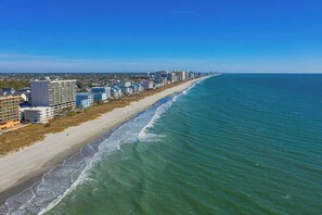 An aerial view of a coastal city with a long beachfront, buildings, and clear skies. - Hermosa Villa Retreat (North Myrtle Beach)