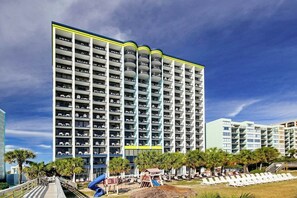 Ein mehrstöckiges Hotel mit Balkonen, einem Poolbereich und einer Rutsche.