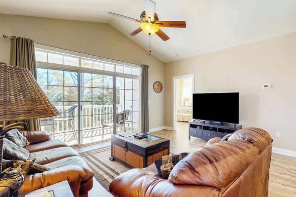 A living room with a sofa, a coffee table, a television, and a ceiling fan. - Serene Barefoot Resort Condo (North Myrtle Beach)