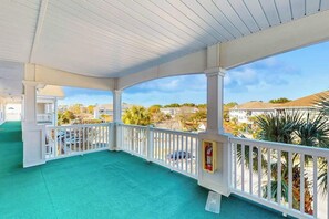 A covered outdoor area with a white railing, a green floor, and a view of the surrounding neighborhood. - Serene Barefoot Resort Condo (North Myrtle Beach)