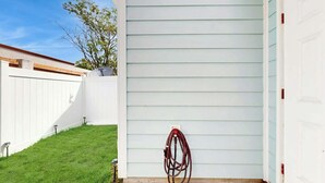 A white garage door, a white fence, and a green lawn. - Gulfstream Cottages 402 (Myrtle Beach)