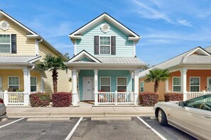 A row of two-story houses with a front porch, a car parked in the driveway, and a clear blue sky. - Gulfstream Cottages 402 (Myrtle Beach)