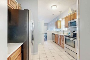 A kitchen with a refrigerator, oven, microwave, and wooden cabinets. - Gulfstream Cottages 402 (Myrtle Beach)