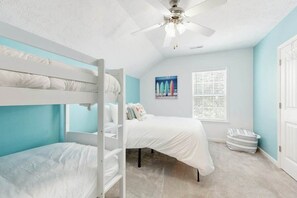A bunk bed room with a ceiling fan, a window with blinds, and a striped bag on the floor. - Gulfstream Cottages 402 (Myrtle Beach)
