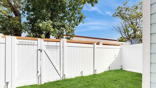 A fenced backyard with a grassy area and a tree. - Gulfstream Cottages 402 (Myrtle Beach)
